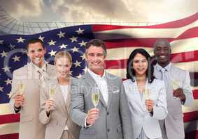Portrait of group of happy businesspeople holding champagne flutes against American flag