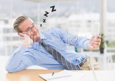 Tired male executive holding phone and relaxing at desk