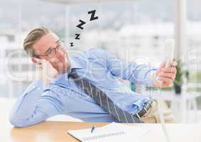 Tired male executive holding phone and relaxing at desk
