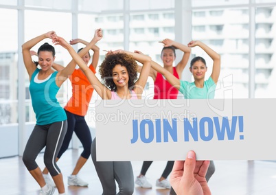 Happy women dancing in fitness studio with hand holding placard in foreground