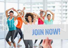 Happy women dancing in fitness studio with hand holding placard in foreground