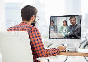 Man having video call with business people on computer at desk
