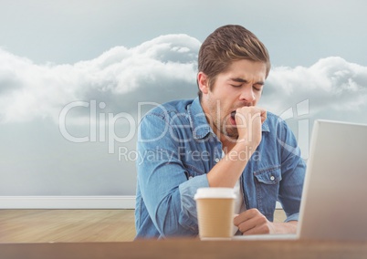 Man yawning at the desk with sky in the background