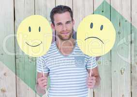 Man holding happy and sad smiley faces