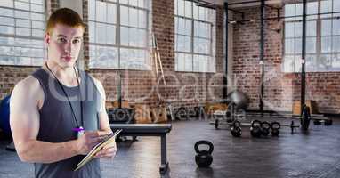 Fitness trainer writing on clipboard in gym