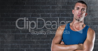 Healthy man standing with arms crossed against brick wall background