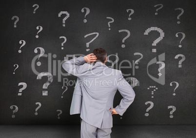 Rear view of businessman looking at questions mark on blackboard