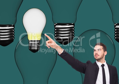 Businessman pointing at light bulb against green background