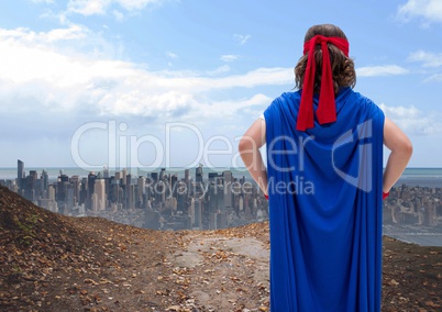 Kid pretending to be a superhero standing against cityscape in background