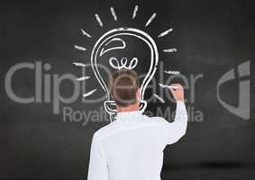Man drawing a light bulb on blackboard