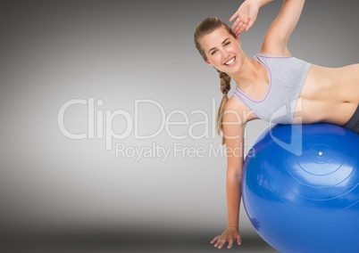 Woman performing exercise with fitness ball against grey background