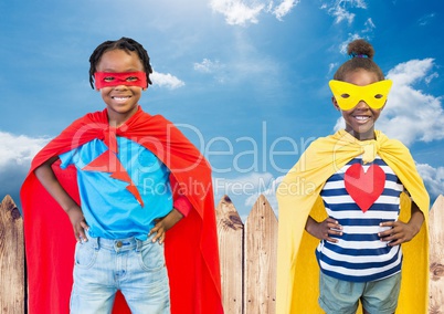 Kids in superhero costume with hands on their waist standing against sky in background