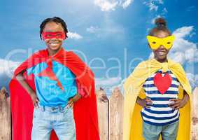 Kids in superhero costume with hands on their waist standing against sky in background