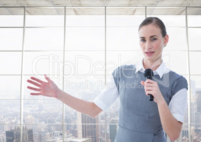 Businesswoman public speaking on microphone against cityscape in background