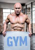 Muscular man holding placard with text gym