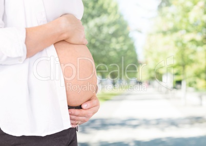 Mid section of pregnant woman with hands on stomach