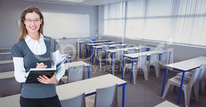 Portrait of smiling woman holding diary in classroom