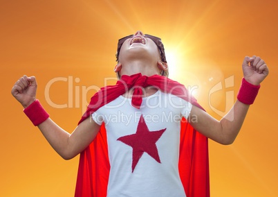 Boy in superhero costume screaming against orange background