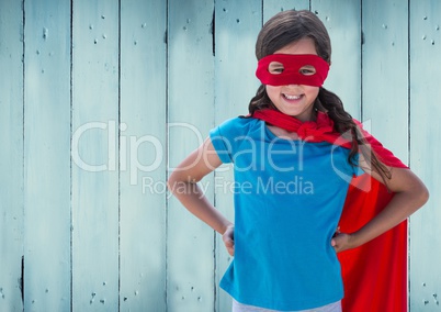 Girl in superhero costume with hands on her hip standing against against wooden background