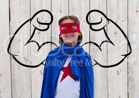 Smiling boy wearing superhero costume standing against wooden background