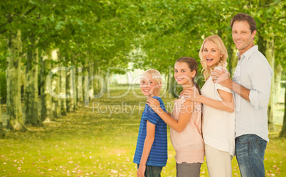 Family standing behind each other against row trees in background