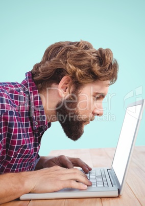 Bearded man looking close to laptop at desk
