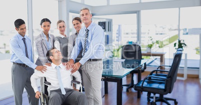 Man sitting in wheelchair and colleagues standing beside him