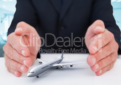 Airplane model surrounded by hands in gesture of protection