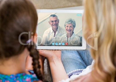 Woman and girl having a video call with senior couple on digital tablet