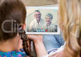 Woman and girl having a video call with senior couple on digital tablet