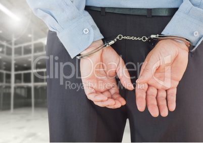 Corrupt businessman in handcuffs standing against built structure