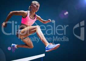 Athlete jumping over hurdles against sky in background