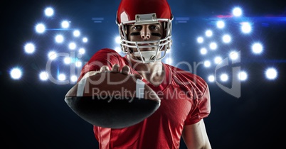 American football player showing ball against spotlight