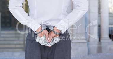 Mid section of corrupt businessman in handcuffs holding money