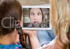 Mother and daughter having video calling in lving room