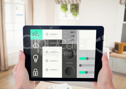 Hand holding digital tablet with home security icons on screen