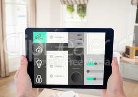 Hand holding digital tablet with home security icons on screen