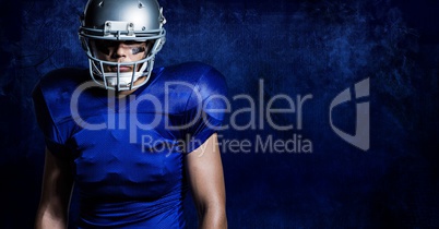 American football player wearing helmet standing against blue background