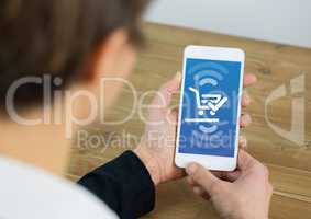 Man holding a mobile phone showing shopping cart on screen