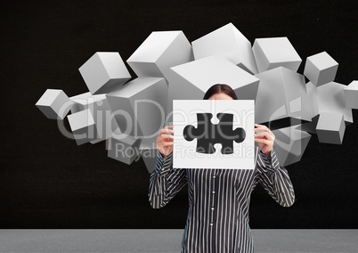 Businesswoman holding sheet of paper showing jigsaw puzzles and white cubes in backgrounds