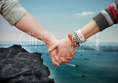 Close-up of couple holding hands with sea in background