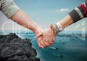 Close-up of couple holding hands with sea in background