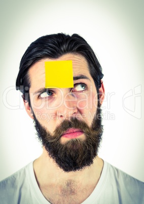 Thoughtful male executive with sticky note on head against white background