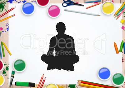 Silhouette of man sitting against stationary items in background