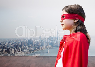 Girl in superhero costume against cityscape background