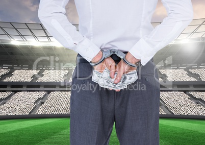 Corrupt businessman in handcuffs holding money at stadium