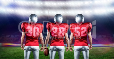 American football players standing with rugby ball in stadium