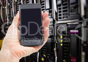 Mans hand holding mobile phone in server room