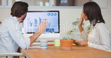 Businesspeople discussing over graphic chart on computer