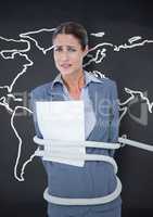 Businesswoman tied up in rope against world map